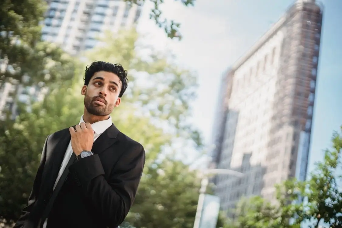 man in black suit, adjusting tie